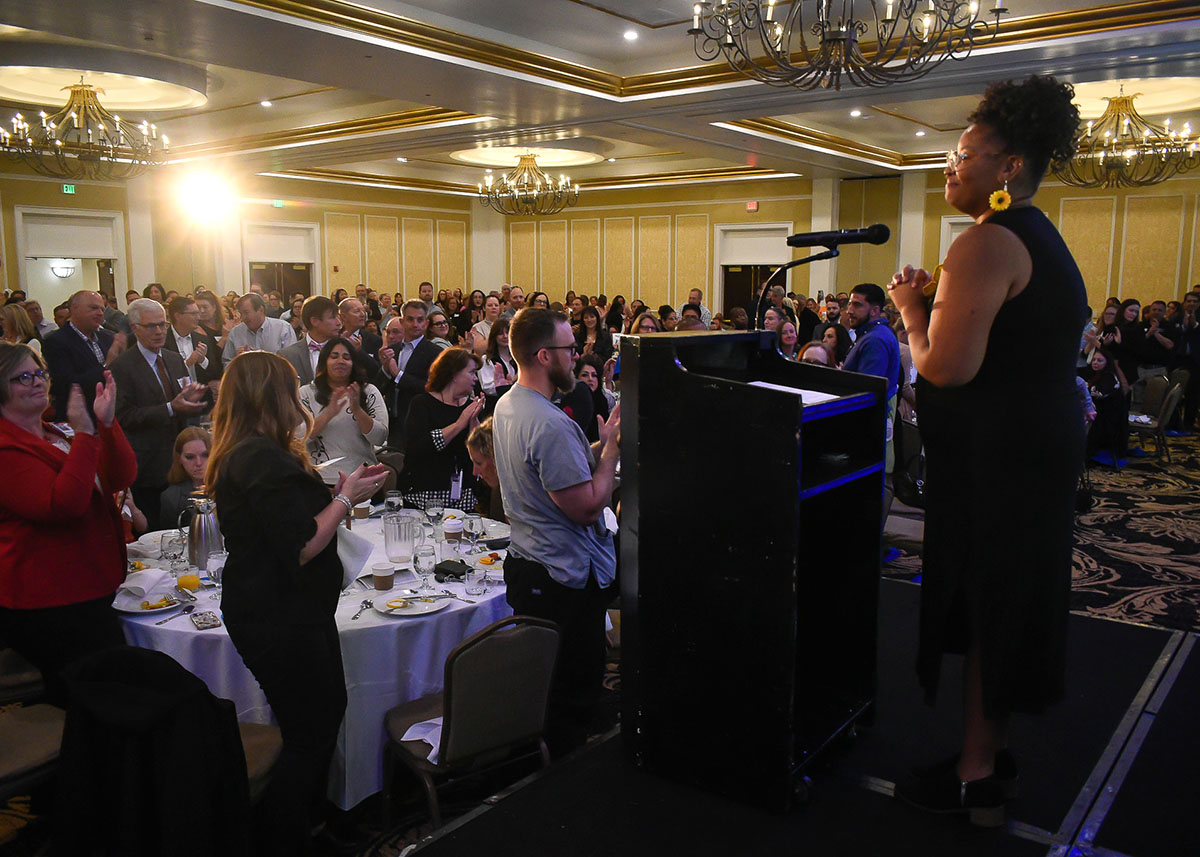 Speaker at annual breakfast with applauding attendees