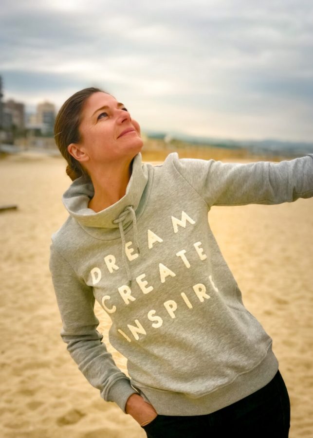 a woman standing on a beach holding a frisbee