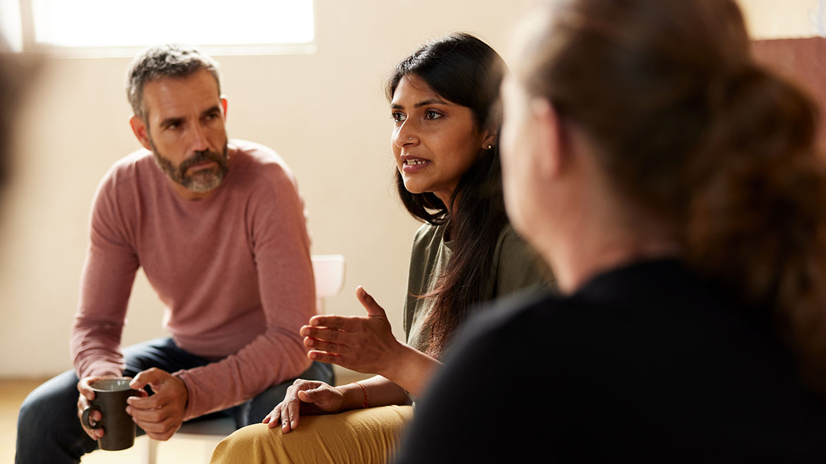 Two parents listening to another woman talk in a group setting