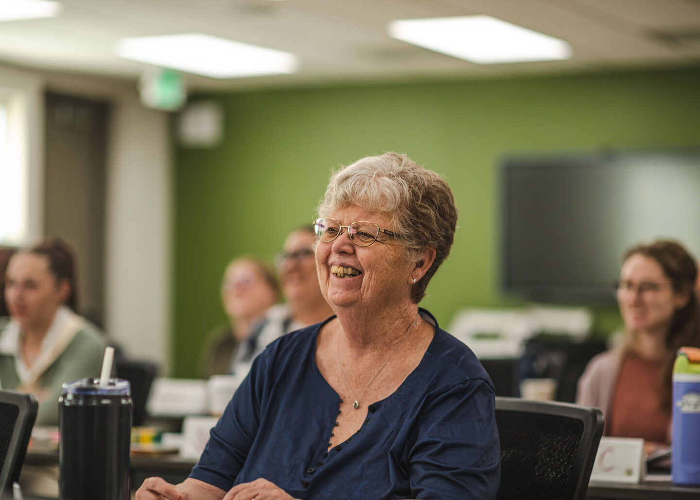 Smiling woman listening to facilitator in classroom