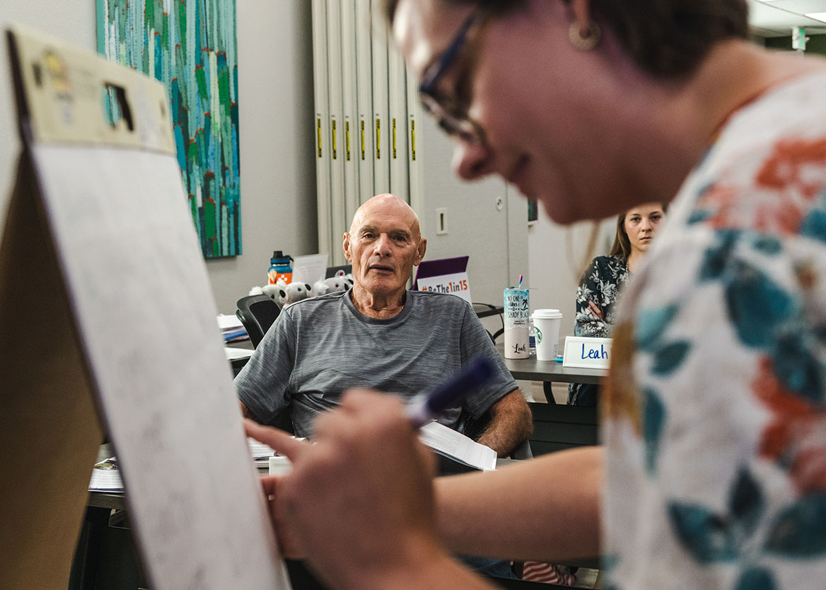 Woman writing on an easel with others listening